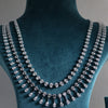 The design showcases a classic tennis-style necklace combined with pear-shaped diamond