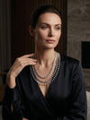 The design showcases a classic tennis-style necklace combined with pear-shaped diamond